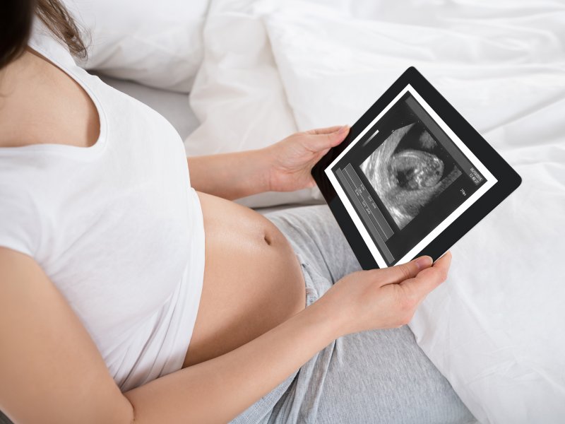 Kobieta w ciąży ze zdjęciem usg na tablecie